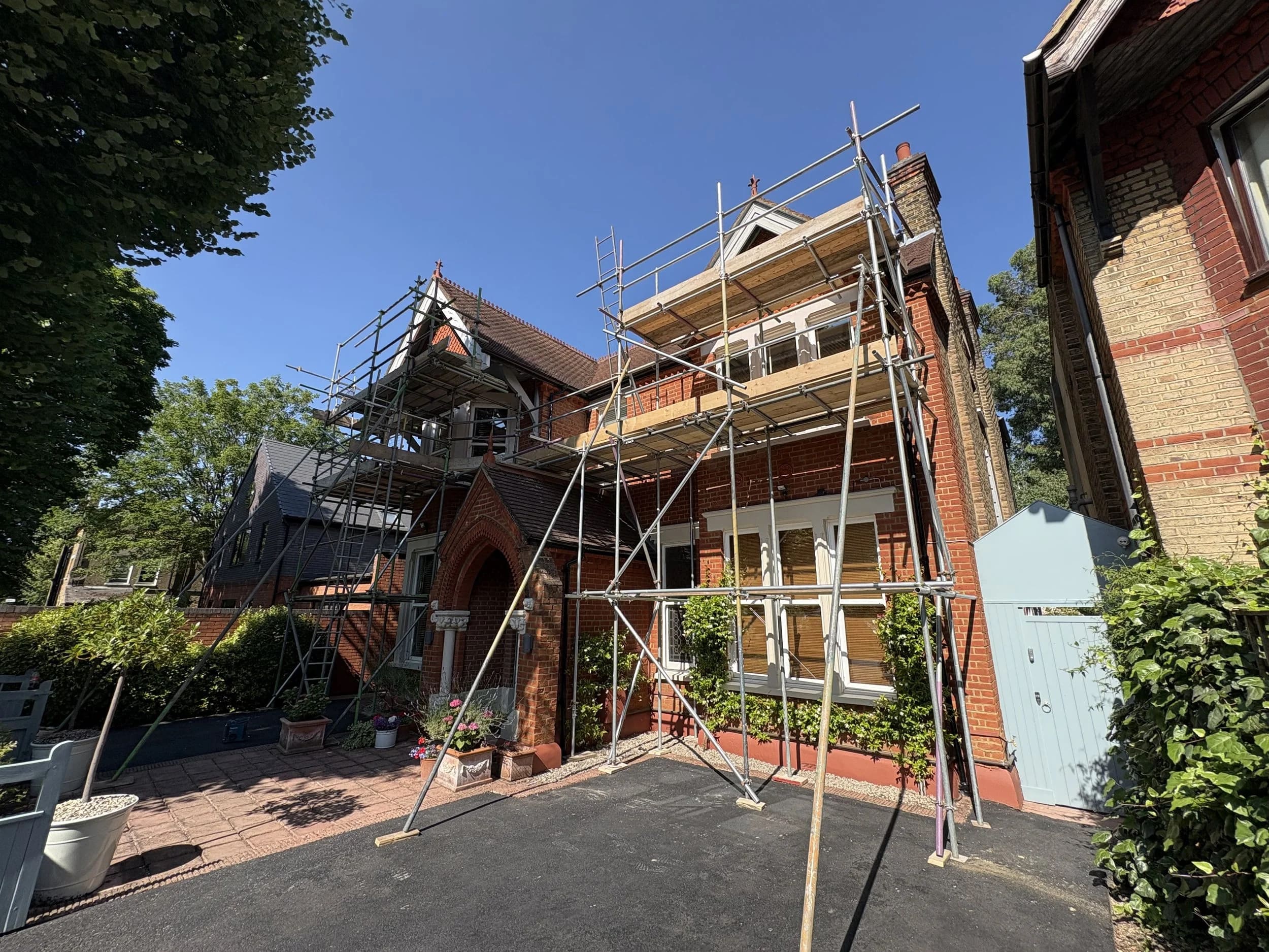 Multi-tier heritage scaffold around a large Victorian Gothic red-brick house for sensitive restoration works