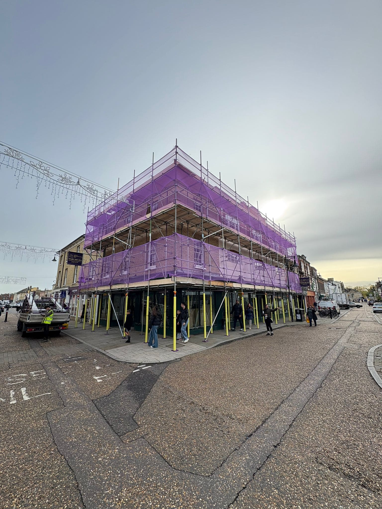 Commercial scaffold with purple debris netting wrapping a three-storey period property on a town high street